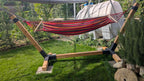 Red and brown striped hammock on a wooden stand in a garden setting